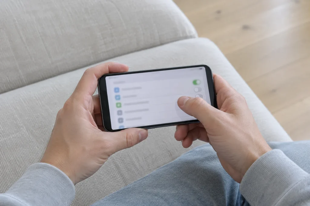 Två händer håller en smartphone med inställningsvyn uppe, redo att uppdatera appar