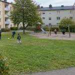 Barn leker i en gård medan ett sitter med en skärm, till ”All skärmtid är inte dålig”